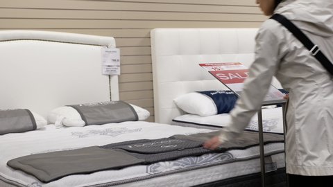 Burnaby, BC, Canada - November 04, 2016 : Woman trying new mattress inside Hudson's Bay store with 4k resolution.