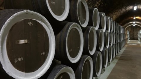 barrel filled with wine in a stack in a wine cellar, pan view