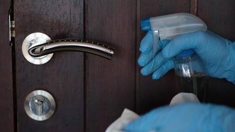 Concept of disinfecting surfaces from bacteria or viruses sill-life, hand cleaning door handle with disinfectant.