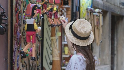 ROVINJ, CROATIA - AUGUST 07, 2019: Girl looking over Pinocchio wooden puppets in street store with handmade souvenirs