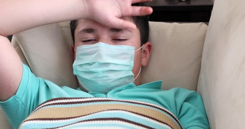Portrait of a caucasion teenage boy in protective medical mask lying at home Virus Flu Pneumonia Coronavirus Covid 19 Epidemic Pandemic