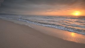 Video with colorful close up view of a sandy beach at sunrise