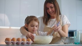 Caucasian mother and daughter having fun while making dough on kitchen. Happy family in the kitchen. Child daughter preparing the dough, bake cookies. - Powered by Shutterstock - Get 15% off with code: PIKWIZARD15