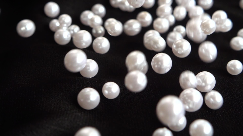White pearls fall on black fabric. Slow motion. | Shutterstock HD Video #1048566910