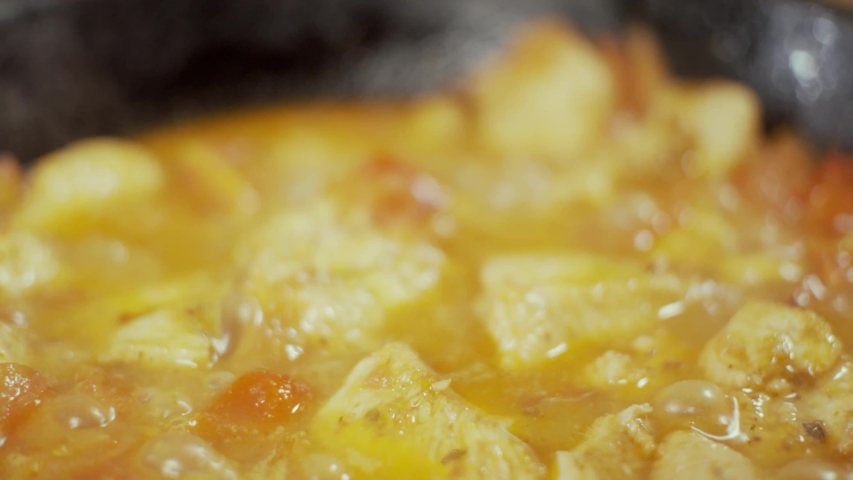 Chicken meat in frying pan, process of frying in oil, shallow depth of field, slow motion