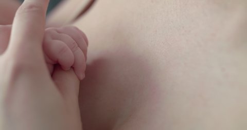 Little baby's hand in mother's hand during breastfeeding. Slowly in 4K