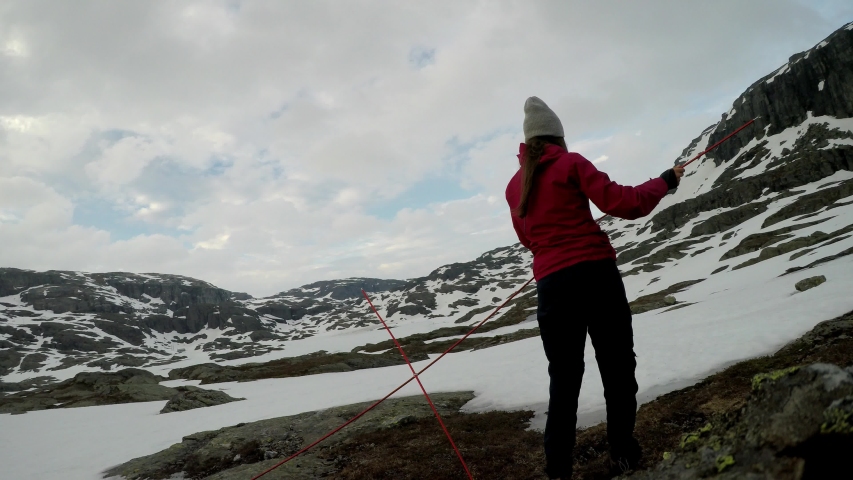 A young couple putting up the tent in the nearby of Trolltunga, Norway. Wild camping in the nature. Couple is having fun. They are surrounded by snow. Winter mountain climbing. Freedom and adventure. 