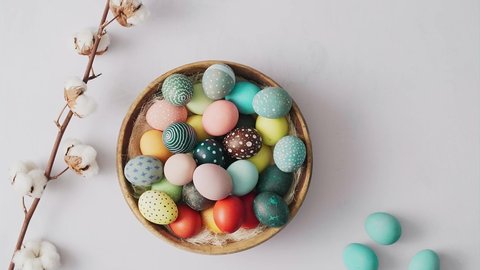 Hands picking up basket with Colorful Easter eggs on bright background. Easter holiday decorations , Easter concept background.