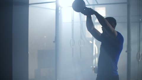 Slow motion: Man doing exercise with kettlebell in gym. fitness athletes men training muscular bodybuilders using kettlebell weights doing intense strength exercise in gym.