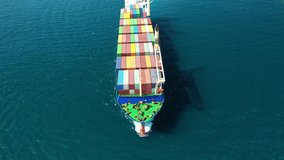Aerial drone top down video of fully loaded large truck size container tanker ship cruising the Mediterranean deep blue sea