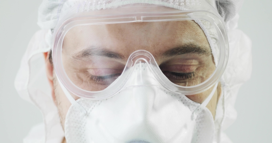 Human man doctor in protective clothes during coronavirus pandemic, portrait. Part of face in suit, mask and glasses on white background in clinic or hospital. Protection from epidemic concept. Royalty-Free Stock Footage #1048617946