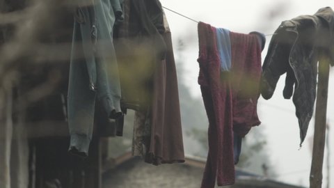 Moody dark laundry clothes gently moving flapping and fluttering in the gentle blowing breeze wind on a string rope washing line in slow motion