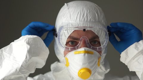 Close portrait of a man in a protective suit wears plastic safety glasses. Medical workers, the threat of the spread of coronavirus Covid19, medical remedies