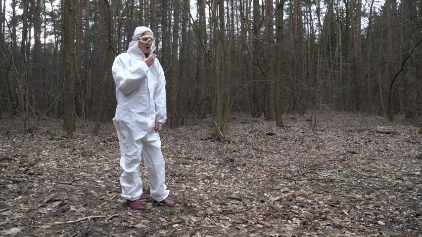 Young woman in a protective suit coughing in the forest.