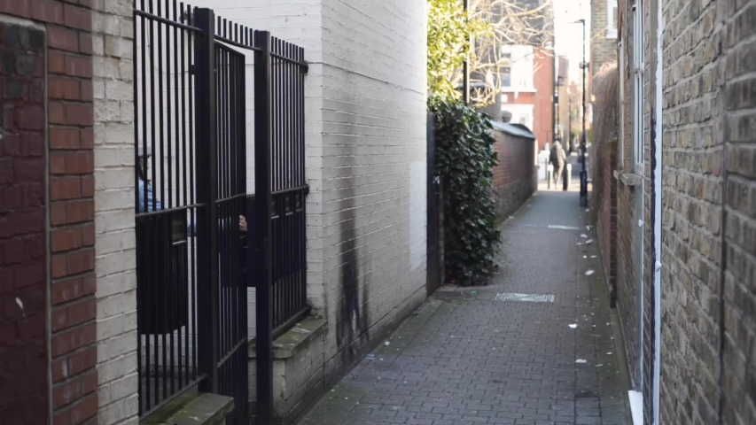 A young woman in a mask walks along the narrow street
