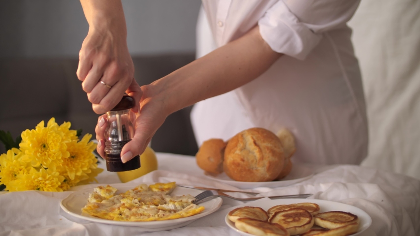 Delicious healthy breakfast with fried scrambled eggs with bread or bun With pepper in woman hands and flowers on the table.
