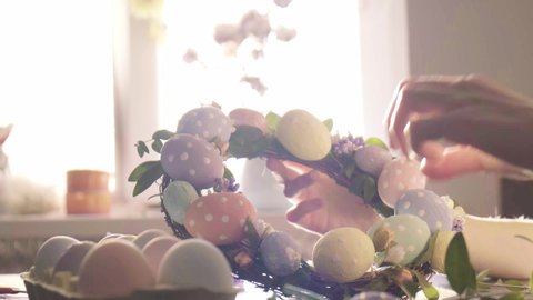 woman makes Easter decoration in the form of an Easter wreath with eggs and flowers