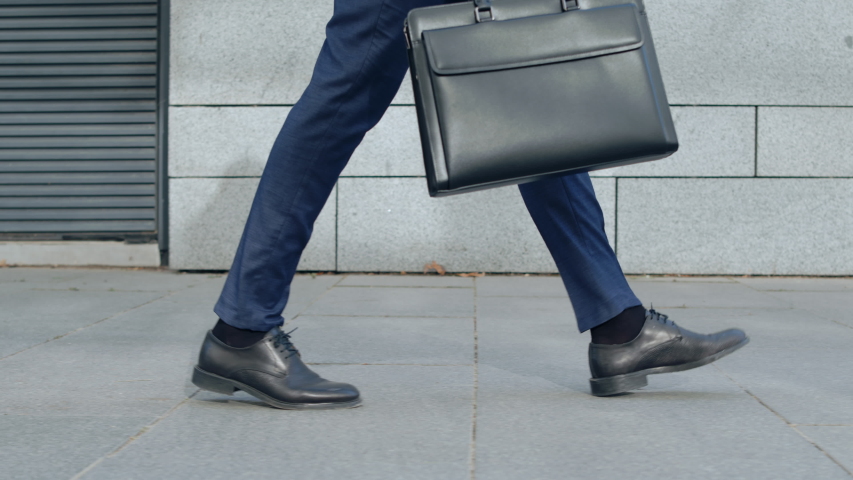 Side view unrecognizable businessman legs walking on city street. Close up male worker with briefcase going for work outdoors in slow motion. Business man in leather shoes walking on sidewalk Royalty-Free Stock Footage #1048639105