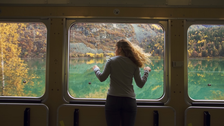 Cinematic and symmetric beautiful shot of young travelling woman, adventurer and female nomad look out of open window of tourist train in swiss mountains. Travel inspiration and wanderlust dreams Royalty-Free Stock Footage #1048640983