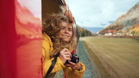 Follow split shot of woman walk to and hang out of train carriage window. Cinematic and inspiring travel blogger live motivational adventure. Happy young woman on train vacation