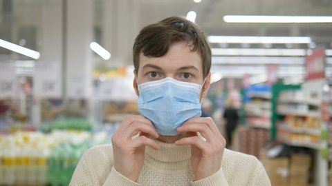 A young man puts on a medical mask to protect against the epidemic, a close-up portrait. Protection from the coronavirus pandemic.