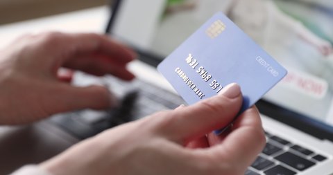 Female hands of cardholder holding credit card making e bank online payment. Woman consumer paying for purchase in web store using laptop technology. Ecommerce website payments concept. Close up view