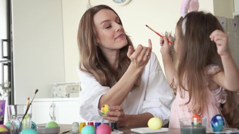 cute daughter with mommy preparing for easter and painting eggs. play with each other. 4K