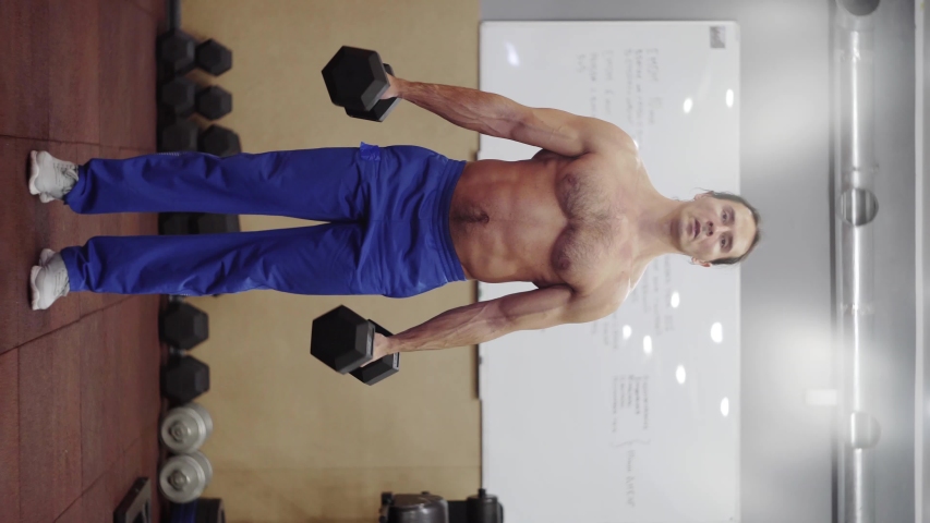 guy does exercises with dumbbells, trains biceps, vertical video Royalty-Free Stock Footage #1048651183