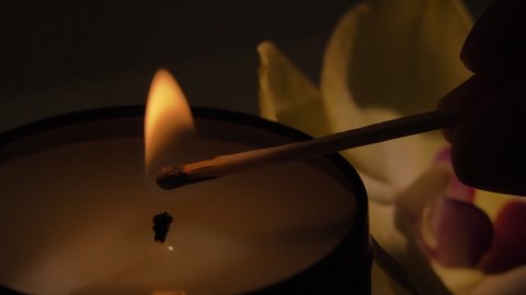 Light candle by match, close up of burning scented soy candle. Aromatherapy, massage, spa concept
