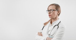 Mature medical specialist with blond hair in white lab coat and eyeglasses looking at camera with serious facial expression. Isolated over white studio background.