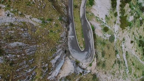 Bikers ride road mountain bikes on serpentine highway. Tour de France route. Sportsmen biking hard trail, aerial view