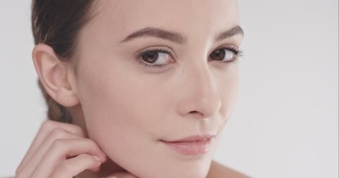 Close up beauty portrait of beautiful woman touching face in slow motion skincare concept shot against grey background shot in 6K Red Epic Dragon