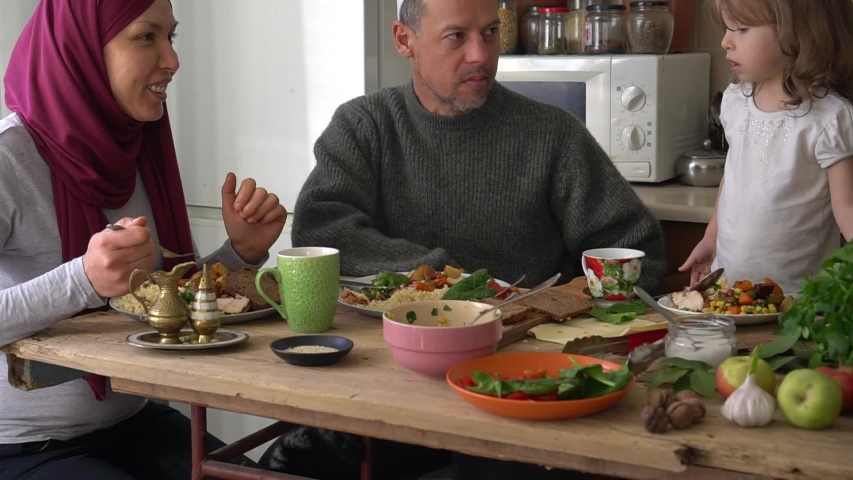 Muslim family having a Ramadan feast. Arab husband and wife, man and woman, children boy and girl, daughter and son eating dinner together at home