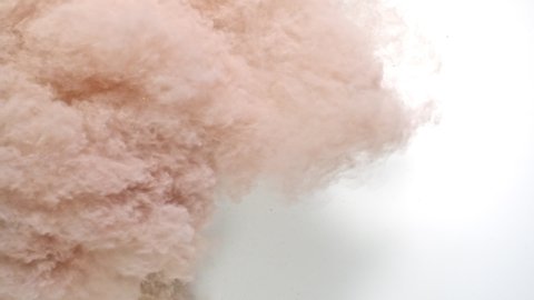 Burst pale pink powder coming in and filling up the frame while creating smoky and dusty powder texture in close up and super slow motion