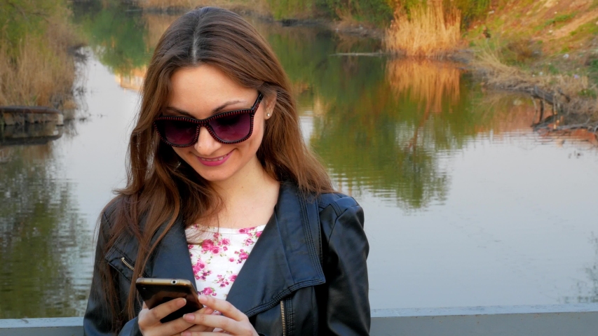 young woman with sunglasses and leather jacket with mobile