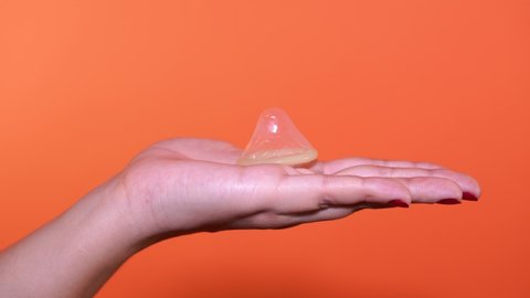 Woman holding condom prevent pregnancy, is her hand holding an open condom, the concept of safe sex. Protection against AIDS and birth control, color background