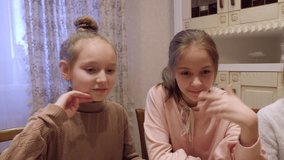 Teenage girls talking, eating and touching camera for turn off. Adorable teen female friends eating tasty meal, chatting and switching camera indoors