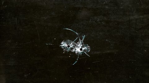 Shot Glass breaking with bullet holes on black background