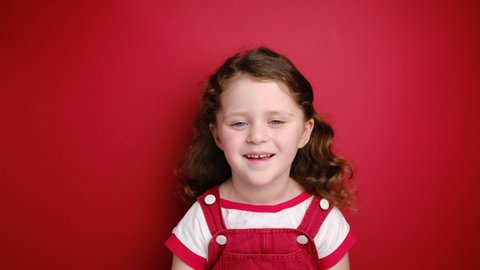 Relaxed little curly girl enjoying good smell or pleasant fragrance, serene mindful child taking deep breath feel no stress free inhaling fresh air relaxing isolated on red studio background