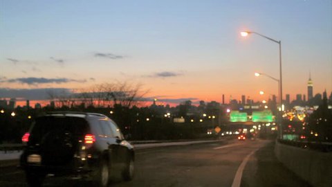NEW YORK - FEB 9, 2010: beautiful sunset over Manhattan Skyline, cars driving on highway headed toward city, NY. Manhattan Skyline is recognized all over the world as the financial capital of NYC, USA