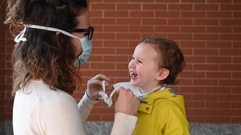 Slow Motion of mother putting face mask on her smiling kid