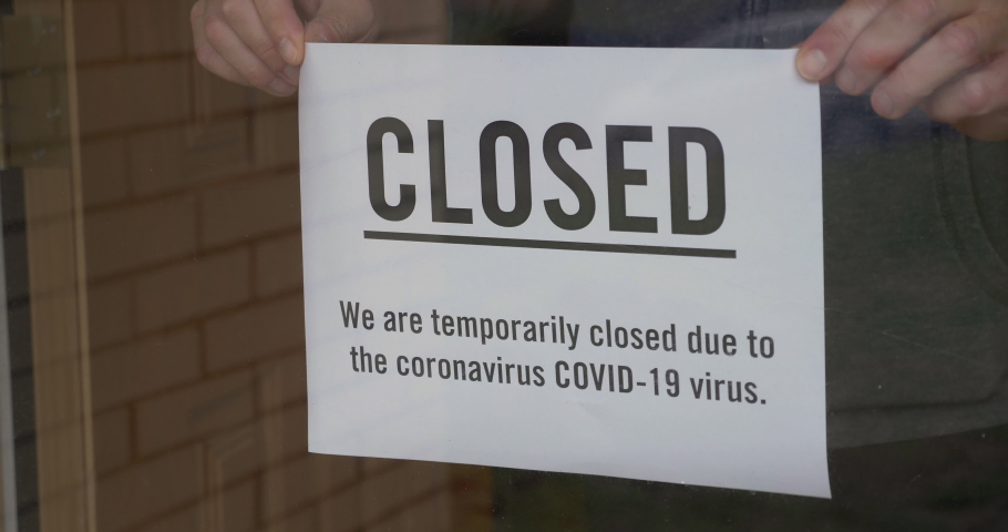 A business owner puts a CLOSED sign on the front door due to the coronavirus COVID19 pandemic.  	 | Shutterstock HD Video #1048684462