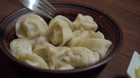 Homemade cooked russian dumplings lie in a plate. Dumplings, pelmeni, ravioli o a brown plate. Bowl of homemade boiled dumplings with butter. Traditional Russian dish pelmeni filled with meat.
