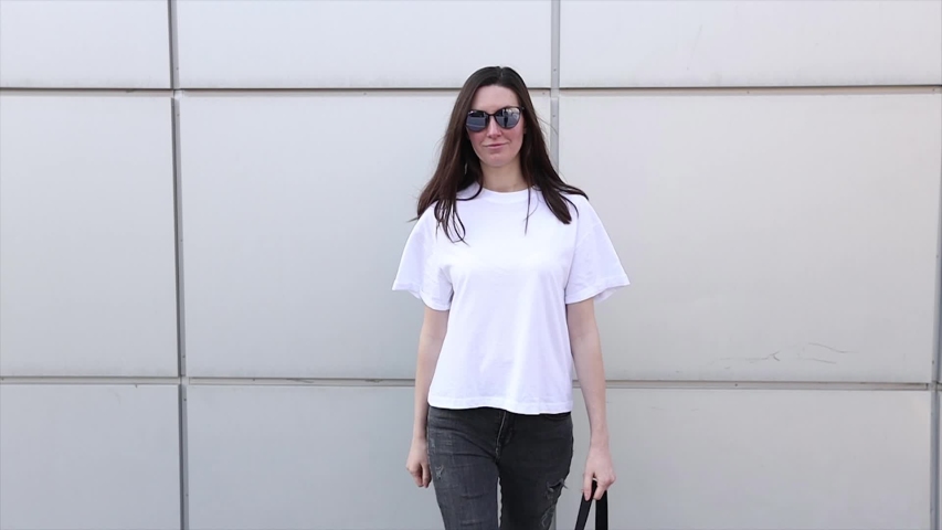 Skinny woman wearing white blank t-shirt and black jeans with space for your logo or mock up design in casual urban style 