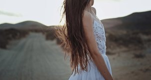 Good looking lady with long hair in a wedding dress in the middle of amazing landscape at sunset she enjoying the time with her self. 4k