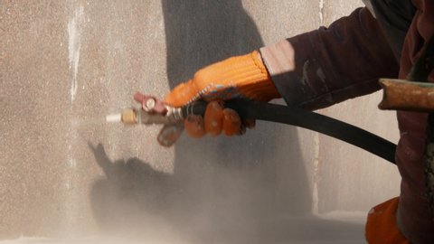 Worker removing graffiti with high pressure cleaner splashing. Cleaning wall using sandblaster gun. Professional cleaning services. Close up 4k