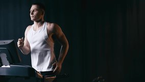 athletic man running on modern treadmill on black