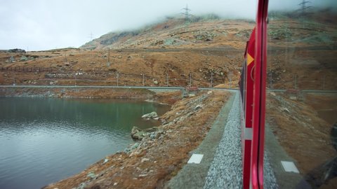 View on bernina express train high up in switzerland mountains. Red vintage train goes around glacier lake. Oldest railway in europe. Amazing travel experience for 2020 destination