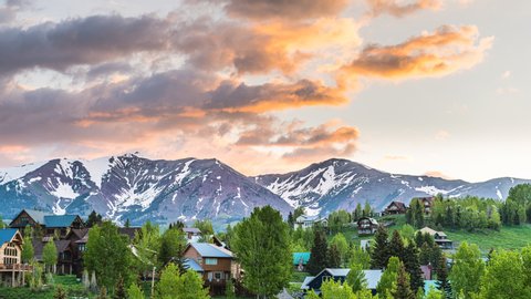 Timelapse time lapse of cityscape of Mount Crested Butte village, small mountain town in Colorado in summer with colorful sunrise by chalet wooden houses on hills with green trees