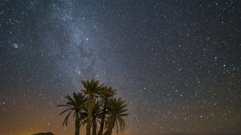 Incredible location in the middle of the desert surrounded by palm trees in Merzouga, Morocco making a timelapse video of the milky way in an amazing dark night till the moon rise at the end.